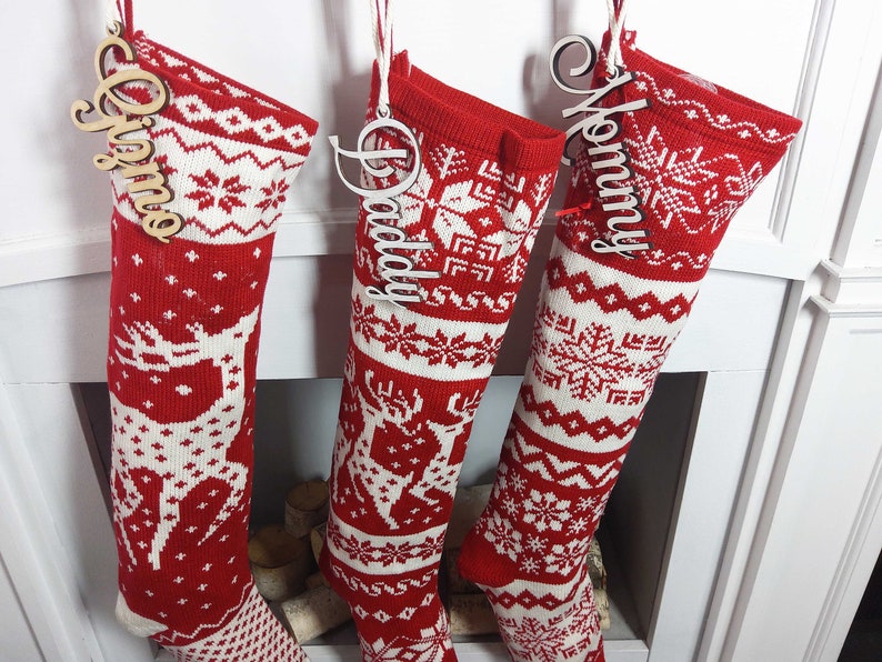 May include: Three red and white knitted Christmas stockings with wooden name tags that say "Mommy", "Daddy", and "Olivia".