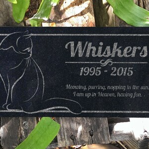 May include: Black granite pet memorial with a white silhouette of a cat and the inscription "Whiskers 1995-2015 Meowing, purring, napping in the sun. I am up in Heaven, having fun."