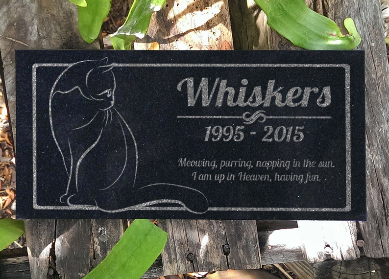 May include: Black granite pet memorial with a white silhouette of a cat and the inscription "Whiskers 1995-2015 Meowing, purring, napping in the sun. I am up in Heaven, having fun."