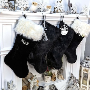 May include: Three black velvet Christmas stockings with white faux fur trim. The stockings are personalized with the names "Max", "Mommy", and "Elfie".