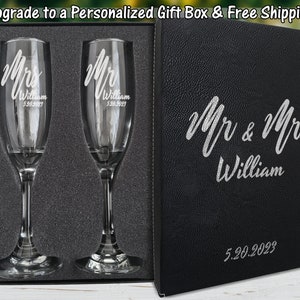 May include: Two champagne flutes with personalized engraving in a black gift box. The flutes are engraved with "Mr. William 5.20.2023" and "Mrs. William 5.20.2023". The gift box is also engraved with "Mr. & Mrs. William 5.20.2023".
