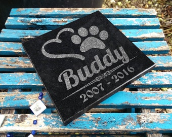 May include: Black granite pet memorial with a paw print and heart design. The name "Buddy" and the dates "2007-2016" are engraved on the stone.