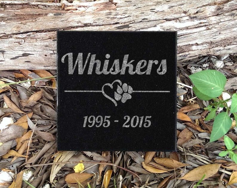 May include: Black granite pet memorial with the name "Whiskers" engraved, a heart with a paw print, and the dates "1995 - 2015".