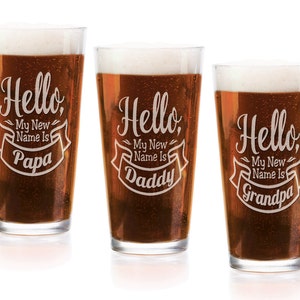 May include: Three clear glass pint glasses filled with amber beer and white foam. Each glass features white etched text that reads Hello, My New Name Is followed by the words Papa, Daddy, or Grandpa inside a decorative banner graphic.