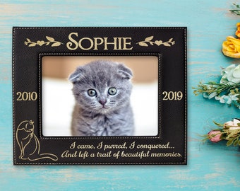 May include: Black leather photo frame with a gold inscription that reads "Sophie 2010 - 2019 I came, I purred, I conquered... And left a trail of beautiful memories."  The frame has a picture of a gray kitten inside.