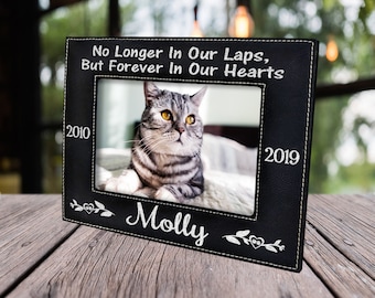 May include: Black leather photo frame with white stitching and the text "No Longer In Our Laps, But Forever In Our Hearts". The frame has a photo of a cat inside with the dates 2010 and 2019 and the name "Molly" written below the photo.