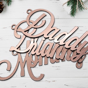 May include: Rose gold metal sign with the words "Daddy" and "Mommy" in a cursive font.