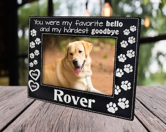 May include: Black leather photo frame with white paw prints and the text "You were my favorite hello and my hardest goodbye". The frame has two white hearts with the years "2004" and "2019" inside. The frame has a photo of a golden retriever dog and the name "Rover" written below the photo.
