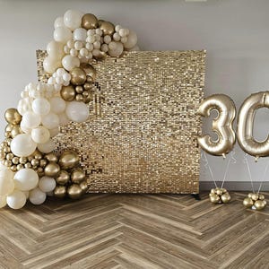 May include: A gold sequin backdrop with a balloon arch in white, cream, and gold. Two large gold number 30 balloons are displayed in front of the backdrop, celebrating a milestone birthday. The balloons are supported by small gold balloon clusters.