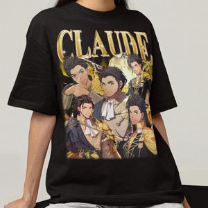 Puede incluir: Camiseta negra con el nombre "CLAUDE" en letras doradas y un collage de ilustraciones de personajes de estilo anime. El diseño presenta múltiples figuras en varias poses, con una estética vintage.