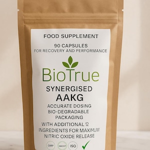 Könnte beinhalten: Ein brauner Beutel mit Nahrungsergänzungsmitteln und einem weißen Etikett. Auf dem Etikett steht "BioTrue Synergised AAKG" und "90 Kapseln für Erholung und Leistung". Mehrere beige Kapseln sind in der Nähe des Beutels zu sehen.