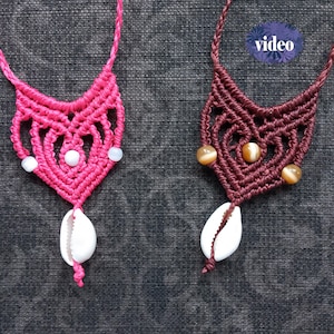 Op de afbeelding: Twee macramé kettingen. Eén is felroze met witte kralen en een witte zeeschelp hanger. De andere is donkerroodbruin met bruine kralen en een witte zeeschelp hanger. Het woord "video" staat in een blauwe cirkel.