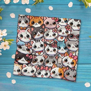 Könnte beinhalten: Ein quadratischer Stoff mit einem sich wiederholenden Muster aus Cartoon-Katzenköpfen in verschiedenen Farben, darunter Grau, Orange und Rosa. Einige Katzen haben Schleifen oder Blumen. Der Hintergrund ist eine hellblaue Holzoberfläche mit weißen Blütenblättern.