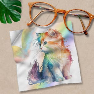 Könnte beinhalten: Ein Mikrofaser-Reinigungstuch mit einer farbenfrohen Aquarell-Illustration einer Katze mit einem Regenbogen-Schwanz. Die Katze sitzt und schaut nach links.