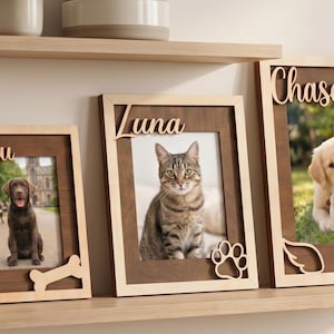 Peut inclure: Trois cadres photo rectangulaires en bois avec des tons clairs et foncés. Les cadres présentent les noms Beau, Luna et Chase en écriture cursive. Les cadres incluent des découpes en forme d'os, de patte et d'ailes d'ange.