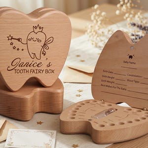 May include: Wooden tooth fairy box in the shape of a tooth. The box is engraved with "Janice's TOOTH FAIRY BOX" and a cartoon tooth fairy. The box opens to reveal a compartment for baby teeth. Includes a space to record baby's birth details.