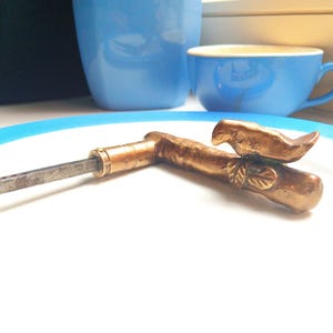 Peut inclure: Une poignée de porte en laiton avec un motif d'oiseau. La poignée est sur une plaque blanche avec un bord bleu.