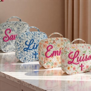 May include: Four personalised floral print lunch bags with embroidered names: "Saw", "Lin", "Emi", and "Luisa". Each bag has a top handle and a quilted design. The names are in pink and blue, with a cross on the "Lin" and "Luisa" bags.