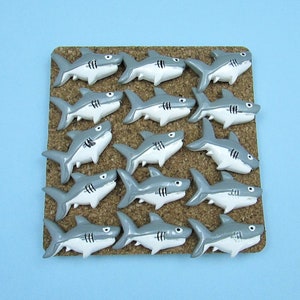 15 Great White Shark Push Pins. They are about an inch long and 1/2 inch high. They come in a metal box with window.