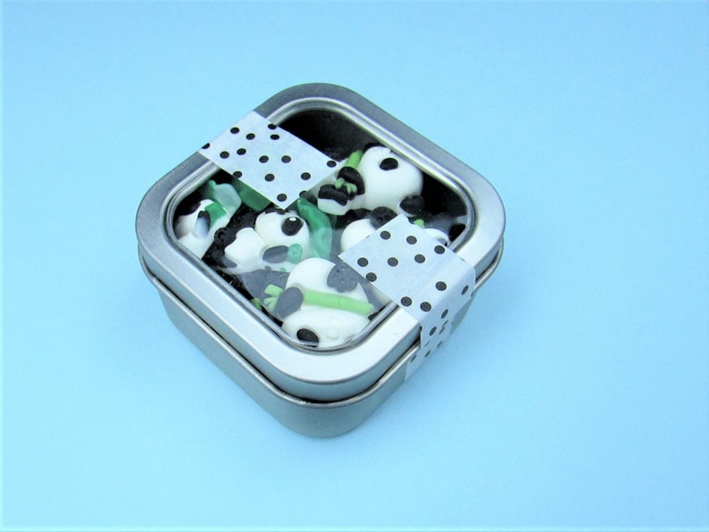 15 Pandas playing with bamboo. Some are wearing leaf hats and holding bamboo and bamboo shoots. Each panda is about 1 inch tall. They come in a metal box with window.