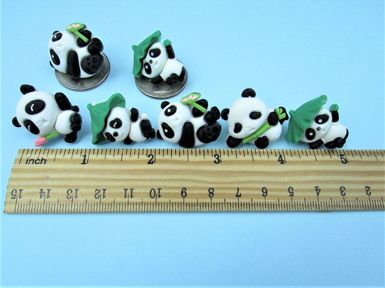 15 Pandas playing with bamboo. Some are wearing leaf hats and holding bamboo and bamboo shoots. Each panda is about 1 inch tall. They come in a metal box with window.