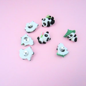 15 Pandas playing with bamboo. Some are wearing leaf hats and holding bamboo and bamboo shoots. Each panda is about 1 inch tall. They come in a metal box with window.