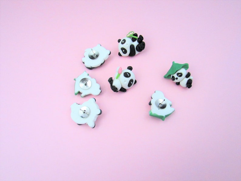 15 Pandas playing with bamboo. Some are wearing leaf hats and holding bamboo and bamboo shoots. Each panda is about 1 inch tall. They come in a metal box with window.
