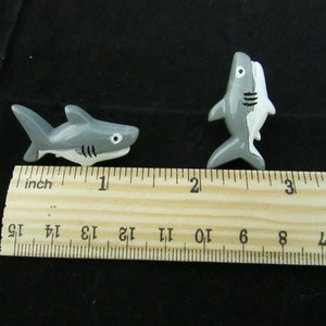 15 Great White Shark Push Pins. They are about an inch long and 1/2 inch high. They come in a metal box with window.