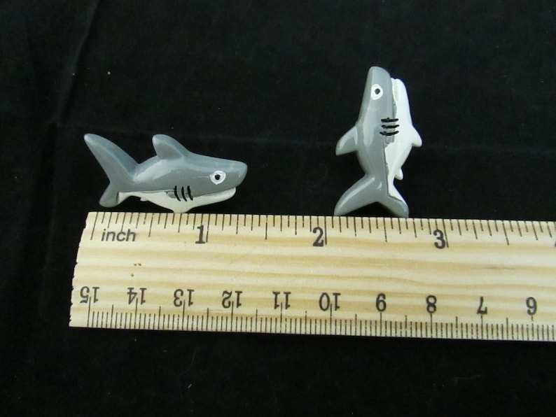 15 Great White Shark Push Pins. They are about an inch long and 1/2 inch high. They come in a metal box with window.