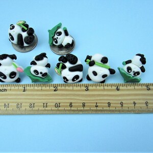 15 Pandas playing with bamboo. Some are wearing leaf hats and holding bamboo and bamboo shoots. Each panda is about 1 inch tall. They come in a metal box with window. Each panda is about the size of a quarter.