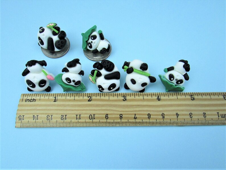 15 Pandas playing with bamboo. Some are wearing leaf hats and holding bamboo and bamboo shoots. Each panda is about 1 inch tall. They come in a metal box with window. Each panda is about the size of a quarter.
