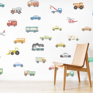 May include: A white wall decorated with colourful cartoon vehicle decals, including a school bus, police car, ambulance, fire truck, excavator, aeroplane, and a helicopter. There is a wooden chair in front of the wall.