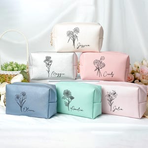 May include: A collection of six cosmetic bags in various pastel colors, each with a floral illustration and a name printed in script. The bags are in white, silver, pink, blue, mint green, and light pink.