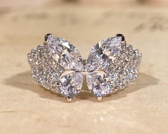 May include: A silver-toned ring featuring a butterfly design composed of two marquise-cut stones at the top and two pear-cut stones at the bottom, with the wings and band encrusted with numerous small, clear, round-cut pavé stones.