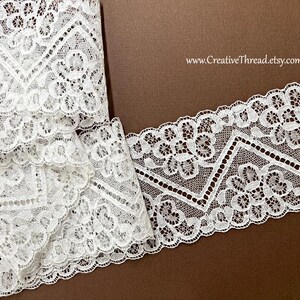 May include: Close-up of white lace trim with a floral and geometric design. The lace is folded and laid on a brown surface. The website address www.CreativeThread.etsy.com is visible in the background.