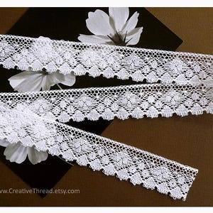 May include: A white ceramic mug with a black handle and the text "But First, Coffee" in a handwritten style. The mug is on a white surface. The mug is approximately 4 inches tall.