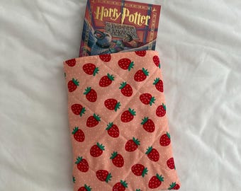 Könnte beinhalten: Eine rosafarbene, gesteppte Buchhülle mit Erdbeermuster. Die Hülle enthält ein Buch mit dem Titel "Harry Potter und der Gefangene von Askaban".