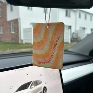 May include: A car air freshener with a pink and orange swirl pattern and the text "EVERYDAY IS A GOOD DAY" in red.