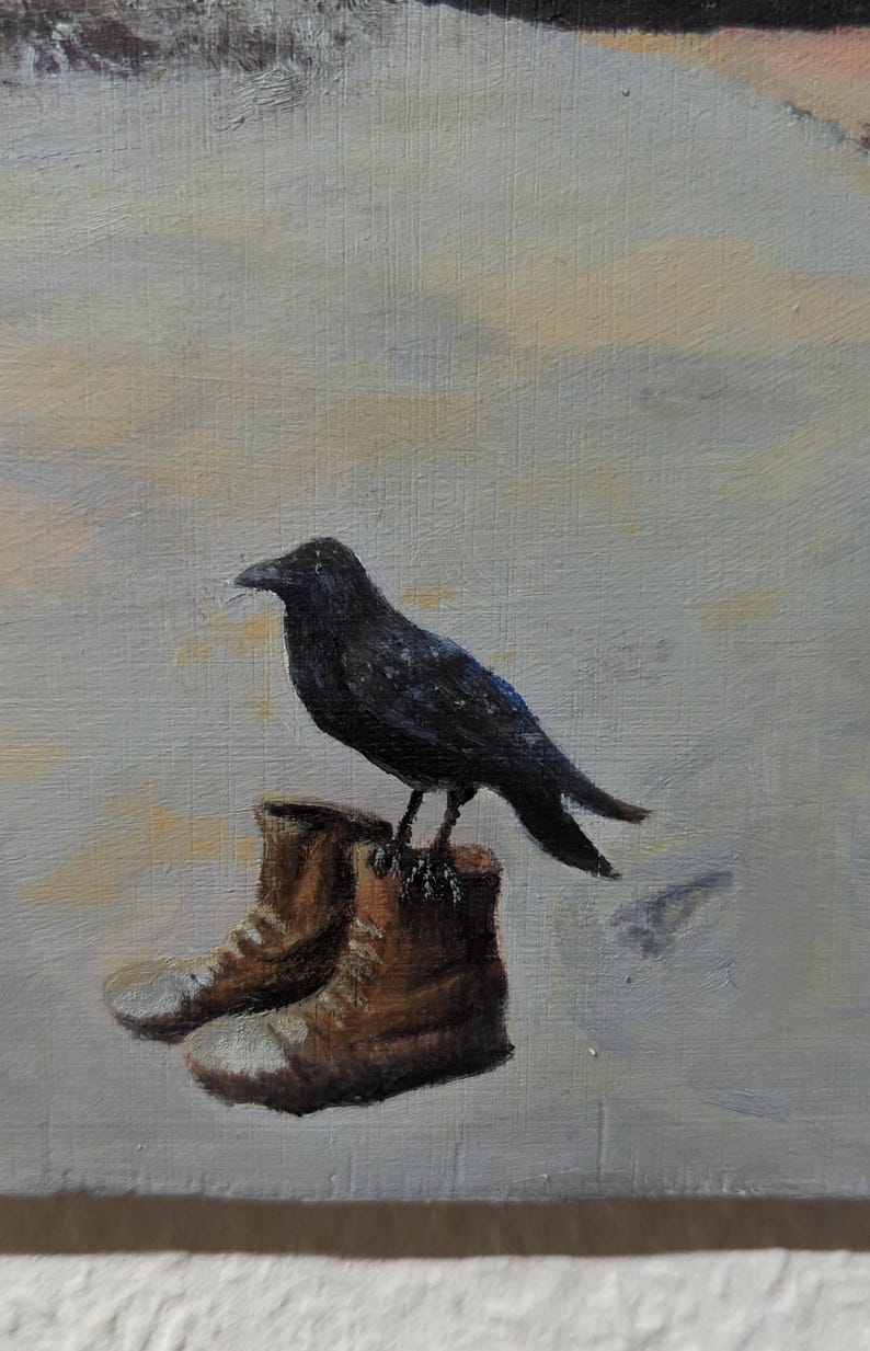 May include: A black crow perched on top of two brown leather boots against a light gray background.