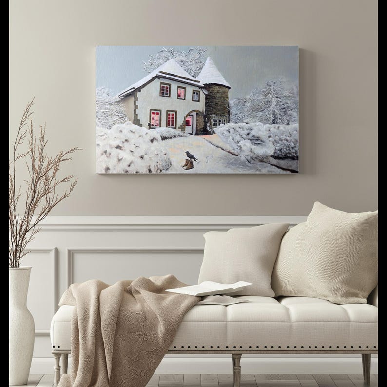 May include: A snowy winter scene with a small house with lit windows and a bird standing on a pair of boots. The house has a white roof and a stone exterior. The scene is framed in a white frame.