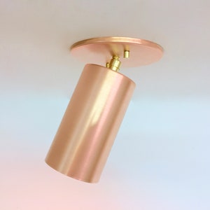 May include: A brushed copper ceiling light fixture with a cylindrical shade and a round mounting plate.