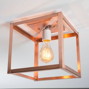 May include: A copper-colored square ceiling light fixture with a single light bulb inside.