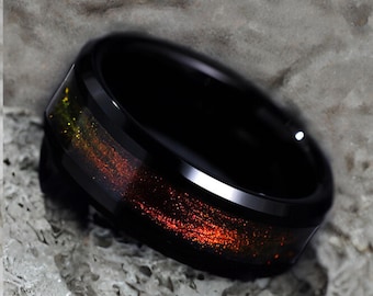 May include: Black tungsten carbide ring with a red and gold inlay. The ring has a beveled edge and a polished finish. Free engraving is offered.
