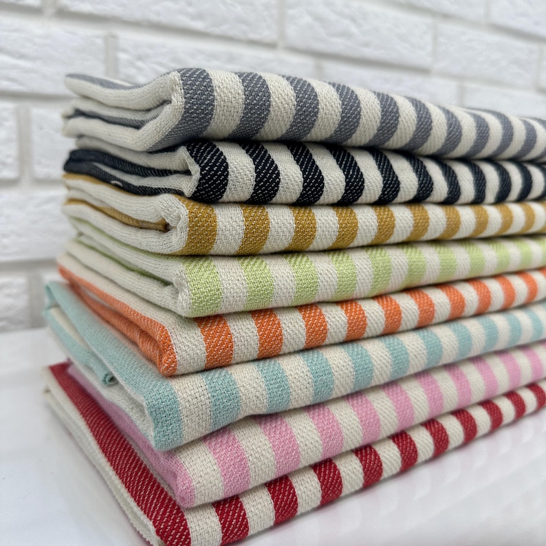 May include: A stack of striped towels in various colors, including gray, black, yellow, green, orange, blue, pink, and red.