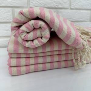 May include: A stack of pink and white striped towels with fringed edges. The towels are folded and rolled up.