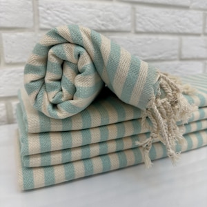 May include: A stack of light blue and white striped towels with fringed edges. The towels are folded and rolled up.
