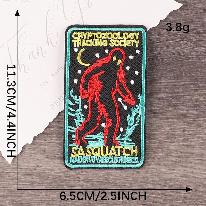 Peut inclure: &Eacute;cusson brod&eacute; avec une silhouette rouge de Sasquatch sur fond noir, avec le texte "CRYPTOZOOLOGY TRACKING SOCIETY" et "SASQUATCH". Le patch mesure 11,3 cm de haut et 6,5 cm de large.