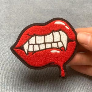Puede incluir: Parche bordado con labios rojos con colmillos y una gota de sangre. El parche tiene un borde negro. Adecuado para ropa o accesorios, un diseño llamativo.