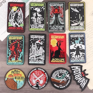 May include: A collection of embroidered patches featuring cryptid creatures and the text "Cryptozoology Tracking Society." Designs include the Jersey Devil, Loch Ness Monster, Mothman, and Sasquatch. Patches are in various shapes and colors.