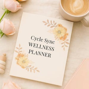 May include: A cream-coloured wellness planner with the text "Cycle Sync WELLNESS PLANNER" and floral accents. The image includes a cup of coffee, pink roses, and a spiral-bound notebook.
